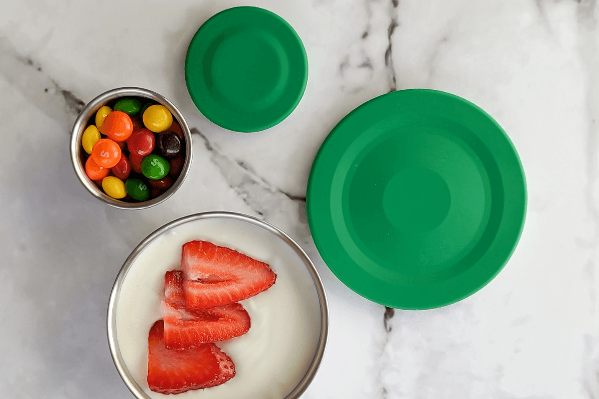 Stainless steel snack pots with yoghurt, chocolate drops and green silicone lids