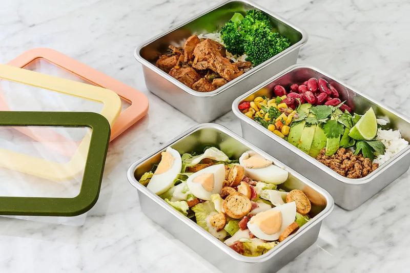three stainless steel food containers with meals in them