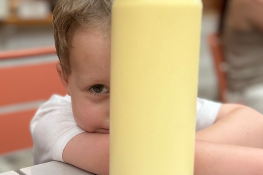 little boy hiding behind a yellow EcoCocoon drink bottle