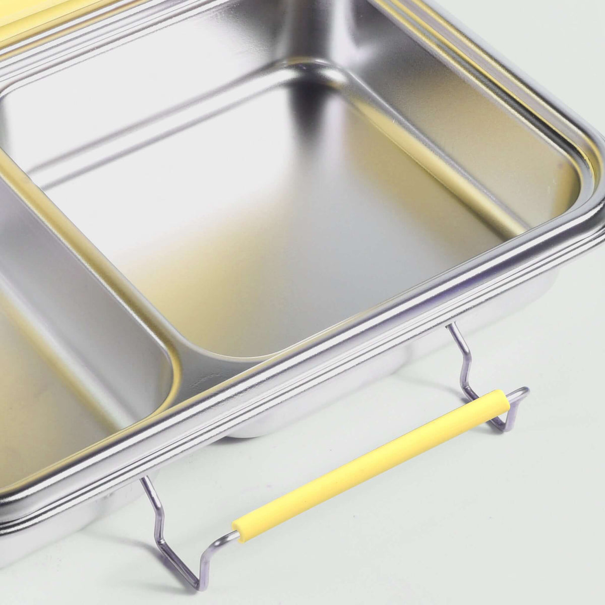 Yellow replacement latch fitted to the side of a two-compartment stainless steel bento box