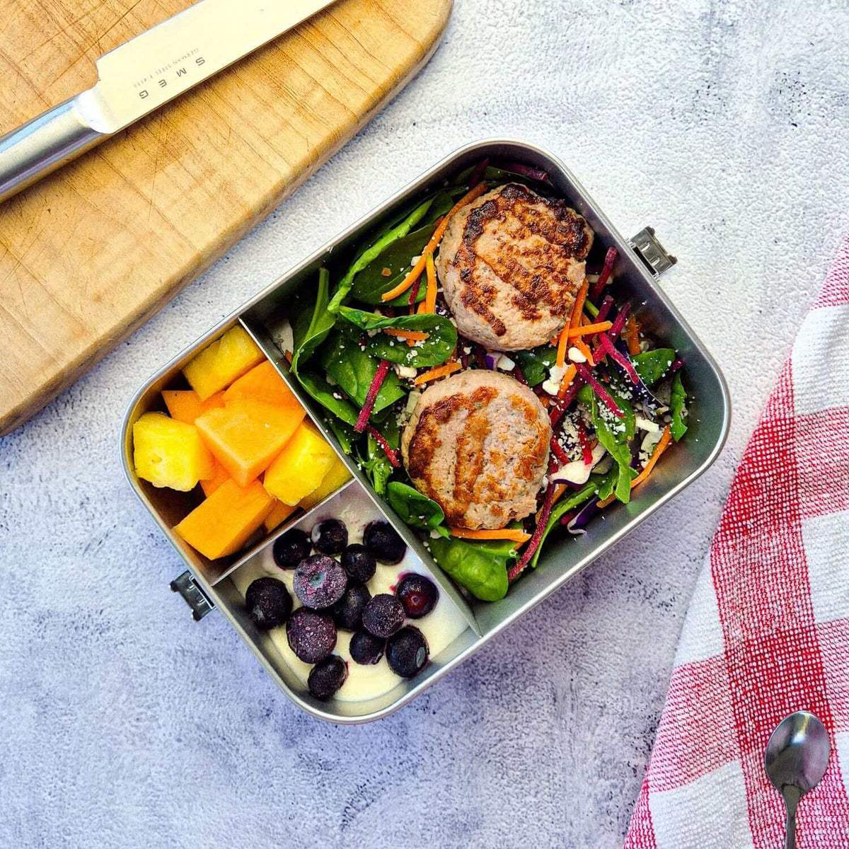Stainless steel bento lunchbox with salad, fruit, and yogurt.