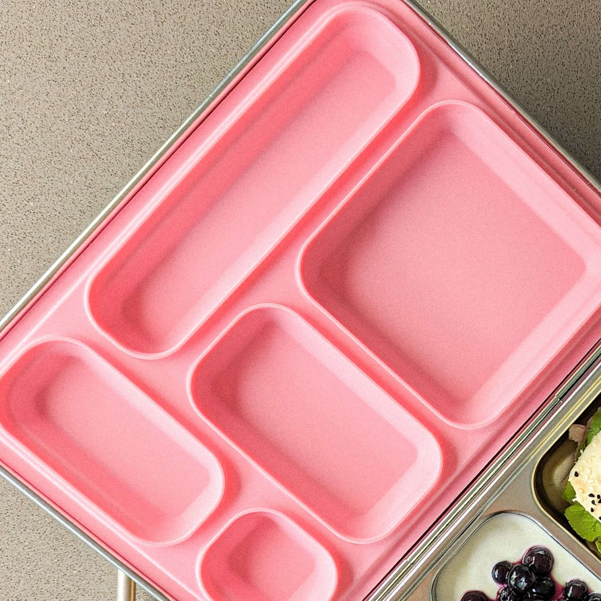 Pink replacement silicone seal seated in a five-compartment stainless steel bento lid