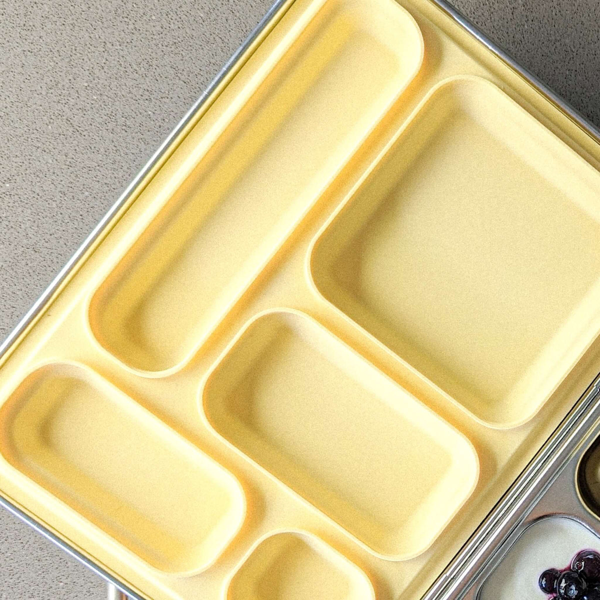 Pale yellow replacement silicone seal seated in a five-compartment stainless steel bento lid