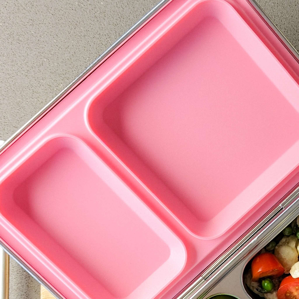 Pink replacement silicone seal seated in a two-compartment stainless steel bento lid
