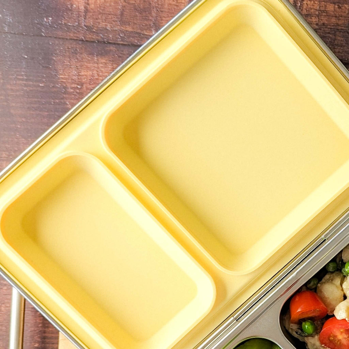 Yellow replacement silicone seal seated in a two-compartment stainless steel bento lid