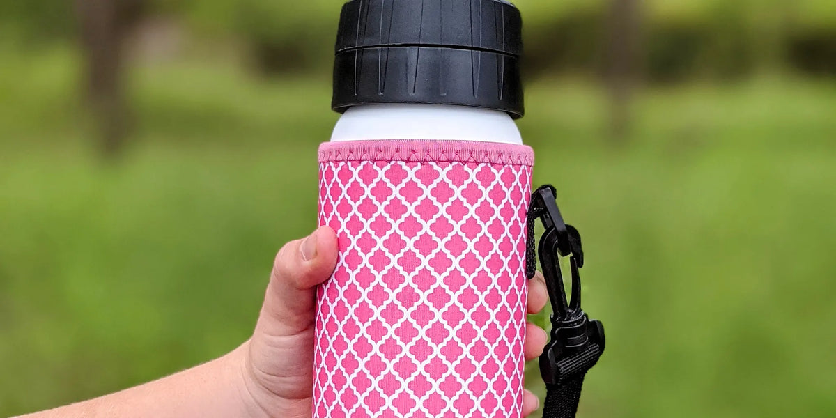 water bottle with pink neoprene cover on it and hand holding the bottle