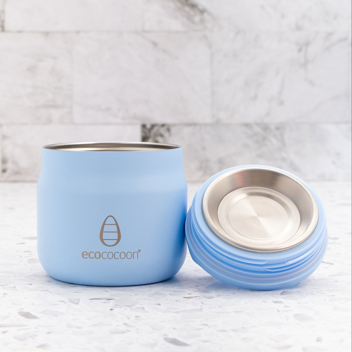 Blue thermos cup with a silver interior on a marble background