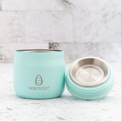 Turquoise reusable coffee cup with lid on a marble background