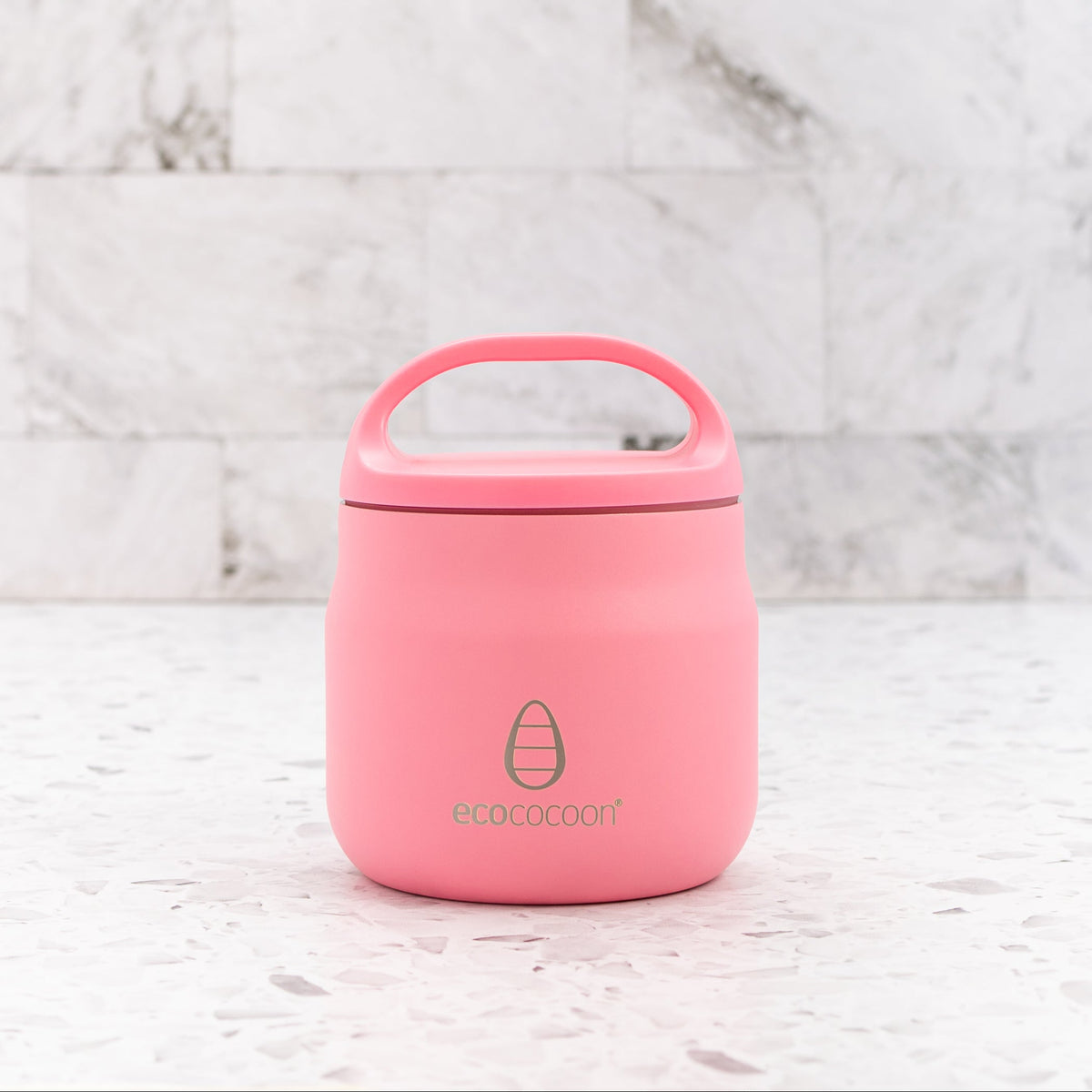 Coral pink insulated stainless steel food jar with a carry-handle lid, on a marble surface