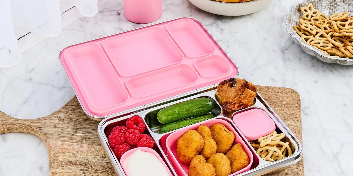 colourful lunchboxes, food jars and stainless steel snack containers stacked in studio setting