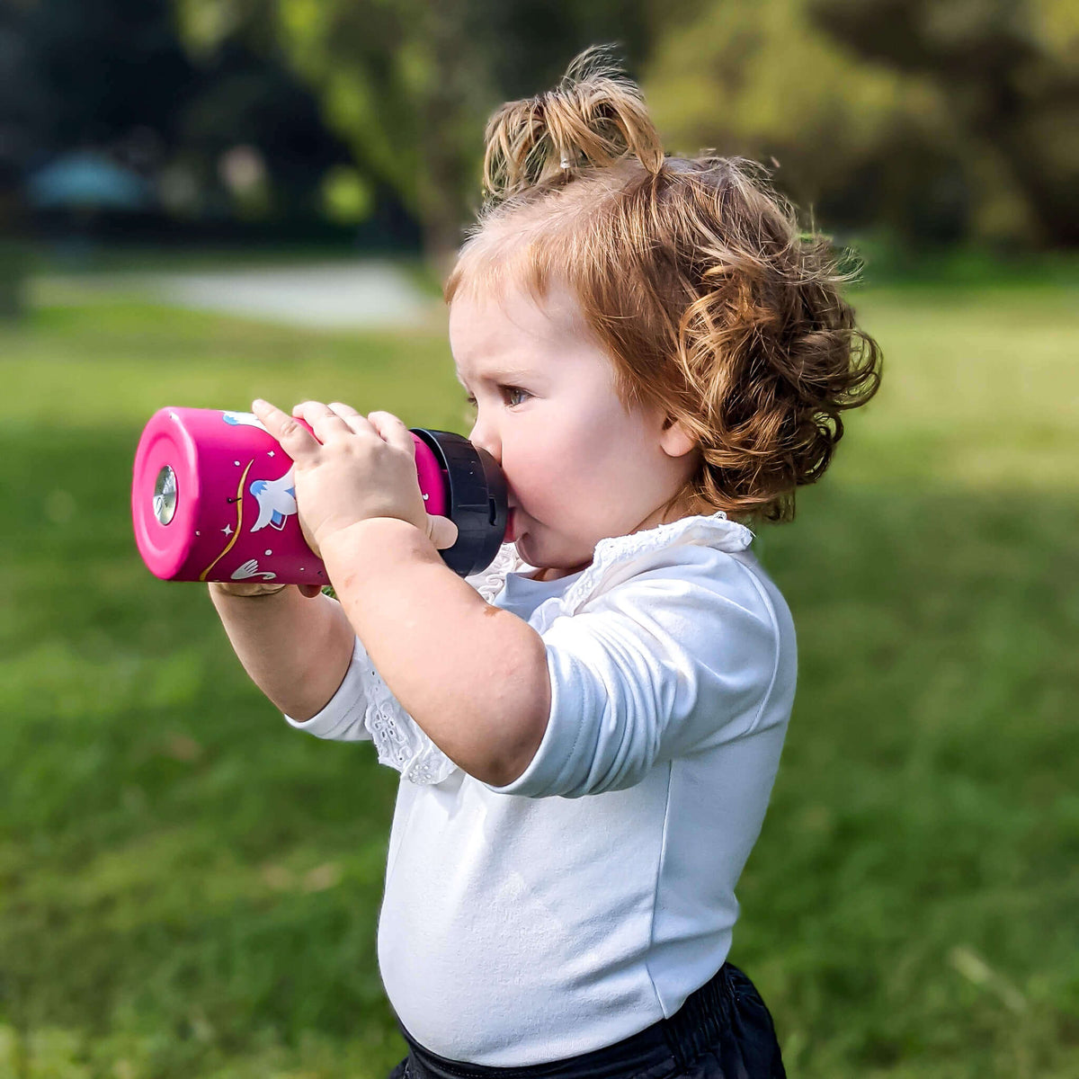 Toddler outdoors drinking from a pink EcoCocoon stainless steel drink bottle