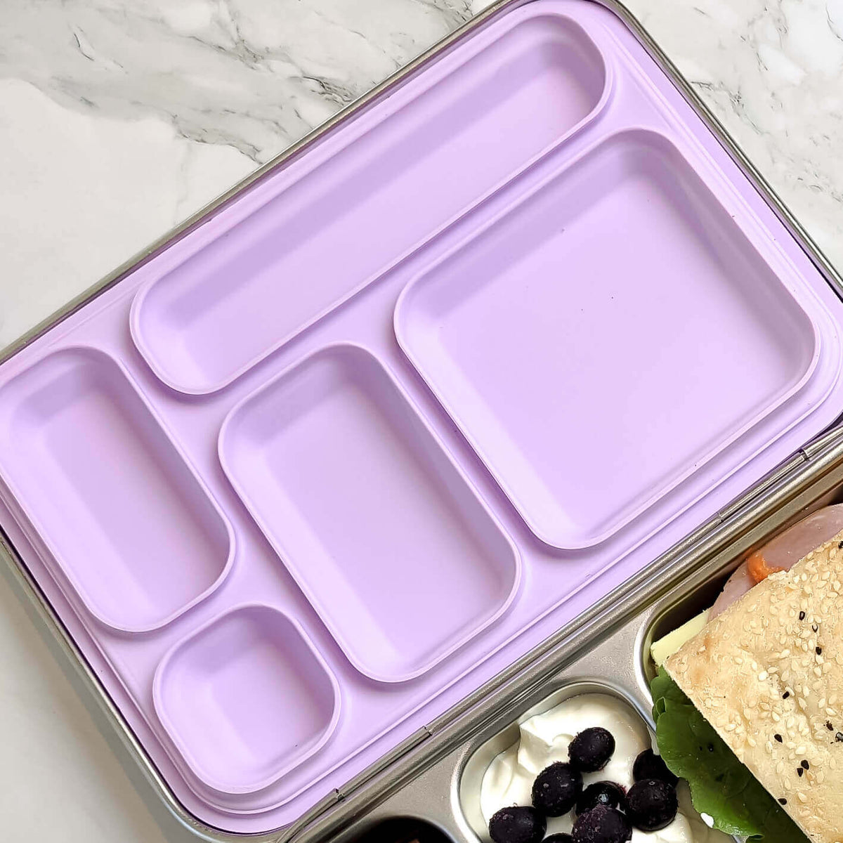 Lilac replacement silicone seal seated in a five-compartment stainless steel bento lid