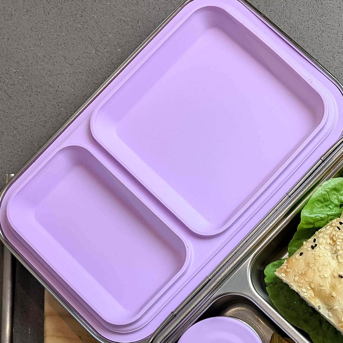 Lilac replacement silicone seal seated in a two-compartment stainless steel bento lid